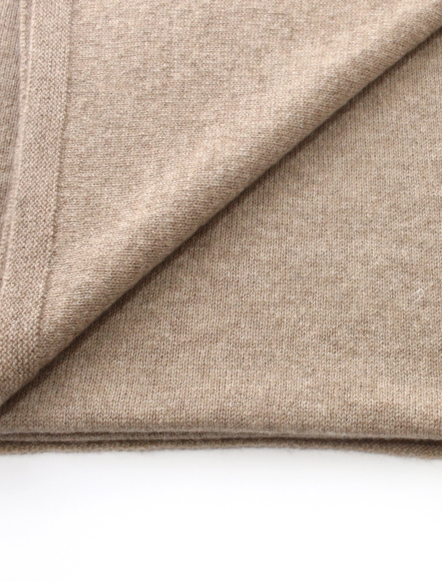 Close-up of ash brown cashmere fabric with a diagonal fold on a white background