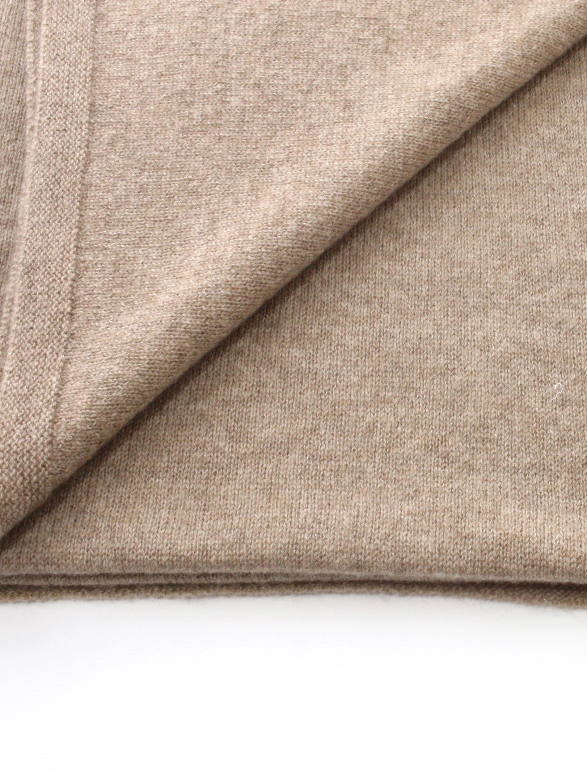Close-up of ash brown cashmere fabric with a diagonal fold on a white background